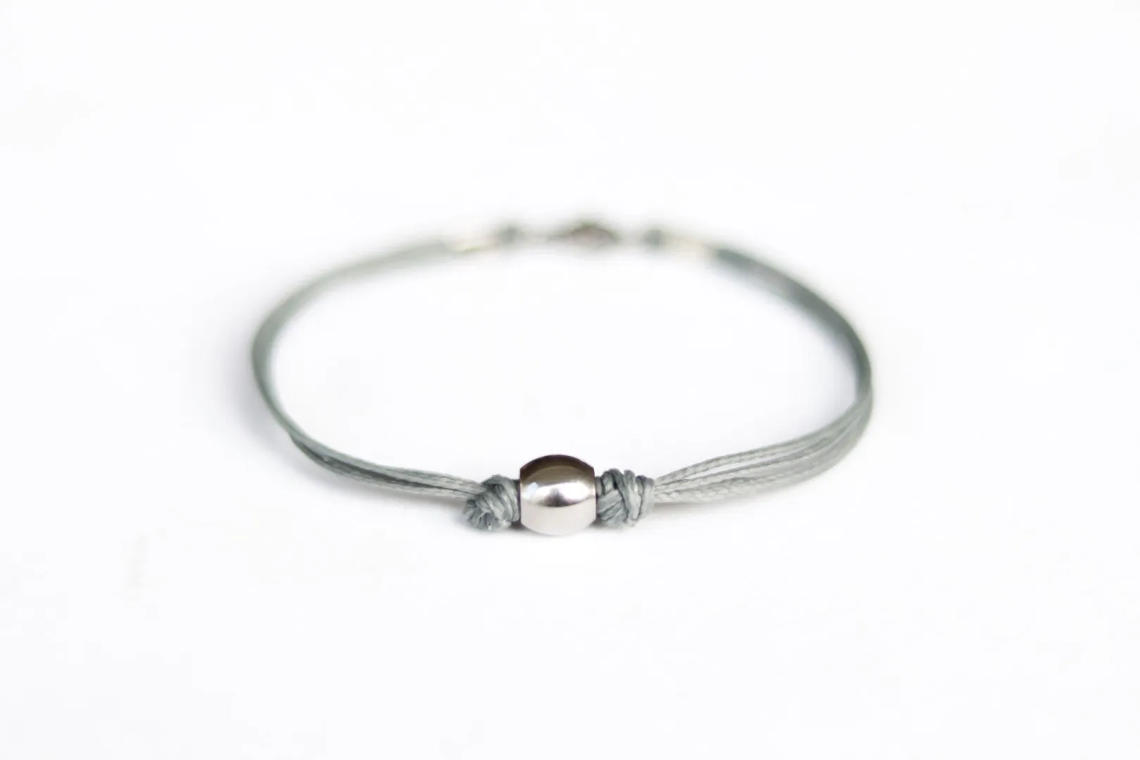 Men's bracelet with silver bead charm and a gray cord